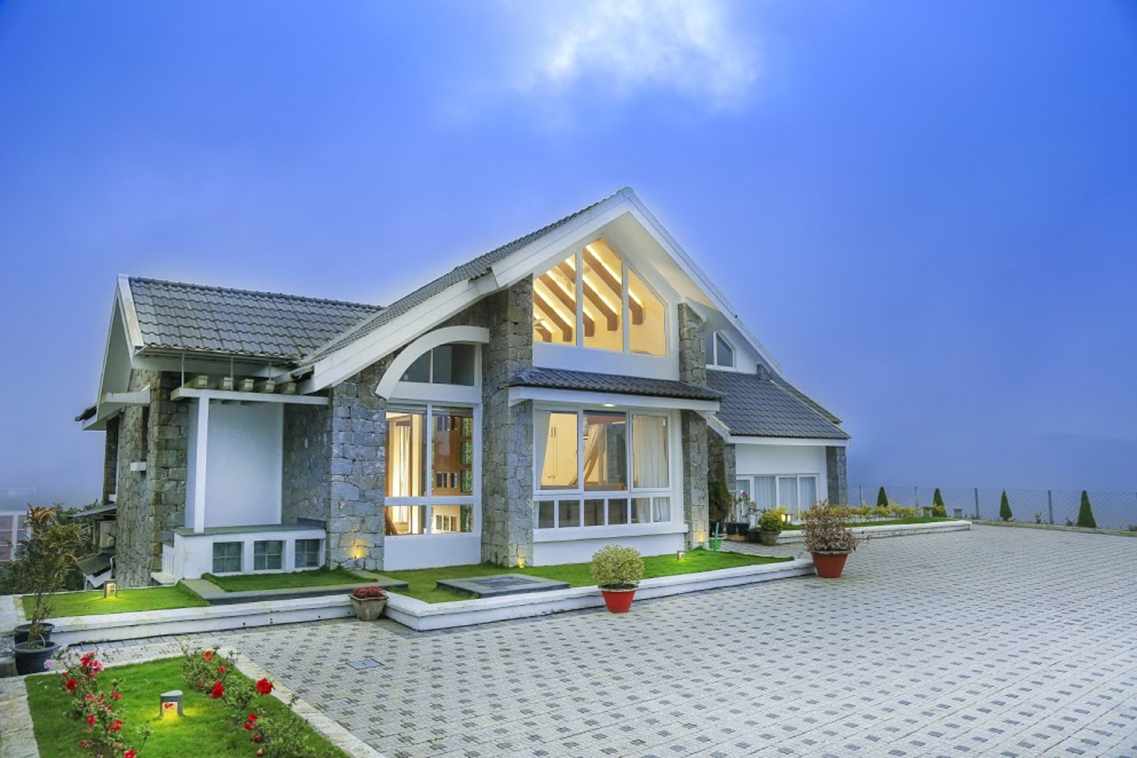 A modern house with a stone facade, large windows, and a well-maintained garden.