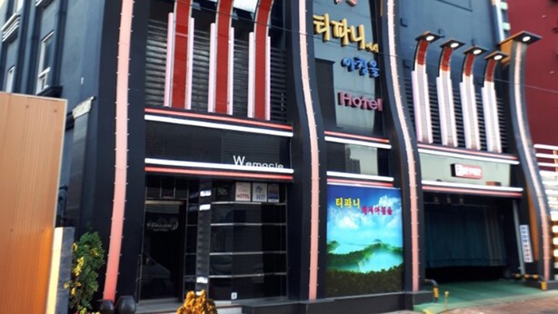 A hotel with a modern facade, featuring a prominent sign with Korean text and a large digital display. - Breakfast at Tiffany's Motel (Mokpo)