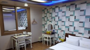 A hotel room with a bed, a desk with a chair, a mirror, and a wall with a geometric pattern. - Breakfast at Tiffany's Motel (Mokpo)