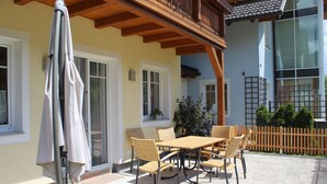 Un patio al aire libre con una mesa, sillas, una pérgola de madera y una cerca.