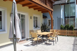 Une terrasse extérieure avec une table et des chaises, une pergola en bois et une clôture.