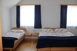 Una habitación con dos camas individuales, cabeceros de madera, mesitas de noche con lámparas y una ventana con cortinas.