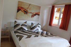 Une chambre à coucher avec un lit, des oreillers, une table de chevet, une lampe et un tableau au mur.