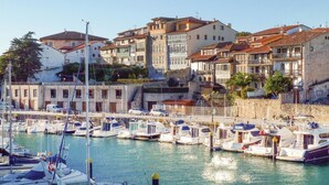 A marina with boats docked, surrounded by historic buildings with red-tiled roofs. - 2 bedroom cozy apartment in Llanes (Llanes)