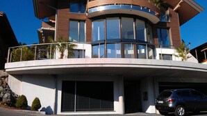 Una casa moderna de dos pisos con un balcón curvo, ventanas grandes y un garaje.