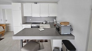 Una cocina moderna con armarios blancos, encimera gris y microondas.