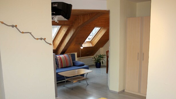 Een kamer met een bed, een bank, een tafel en een kledingkast.