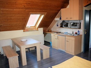 Een compacte keuken met houten kastjes, een ingebouwde magnetron en een klein raam.