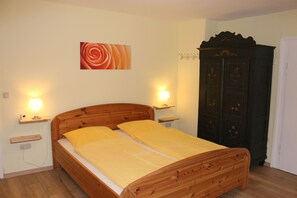 Une chambre à coucher avec un lit en bois, des lampes de chevet, une œuvre d’art murale et une armoire en bois foncé.