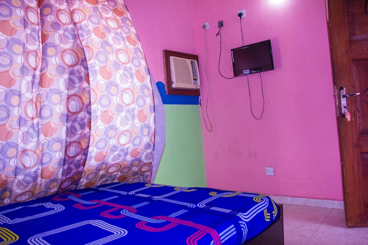 Ein Schlafzimmer mit einem Bett, einem Fernseher und einer Klimaanlage an der Wand.