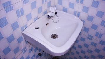 A bathroom with a white sink, blue and white checkered tiles, and a visible drain.