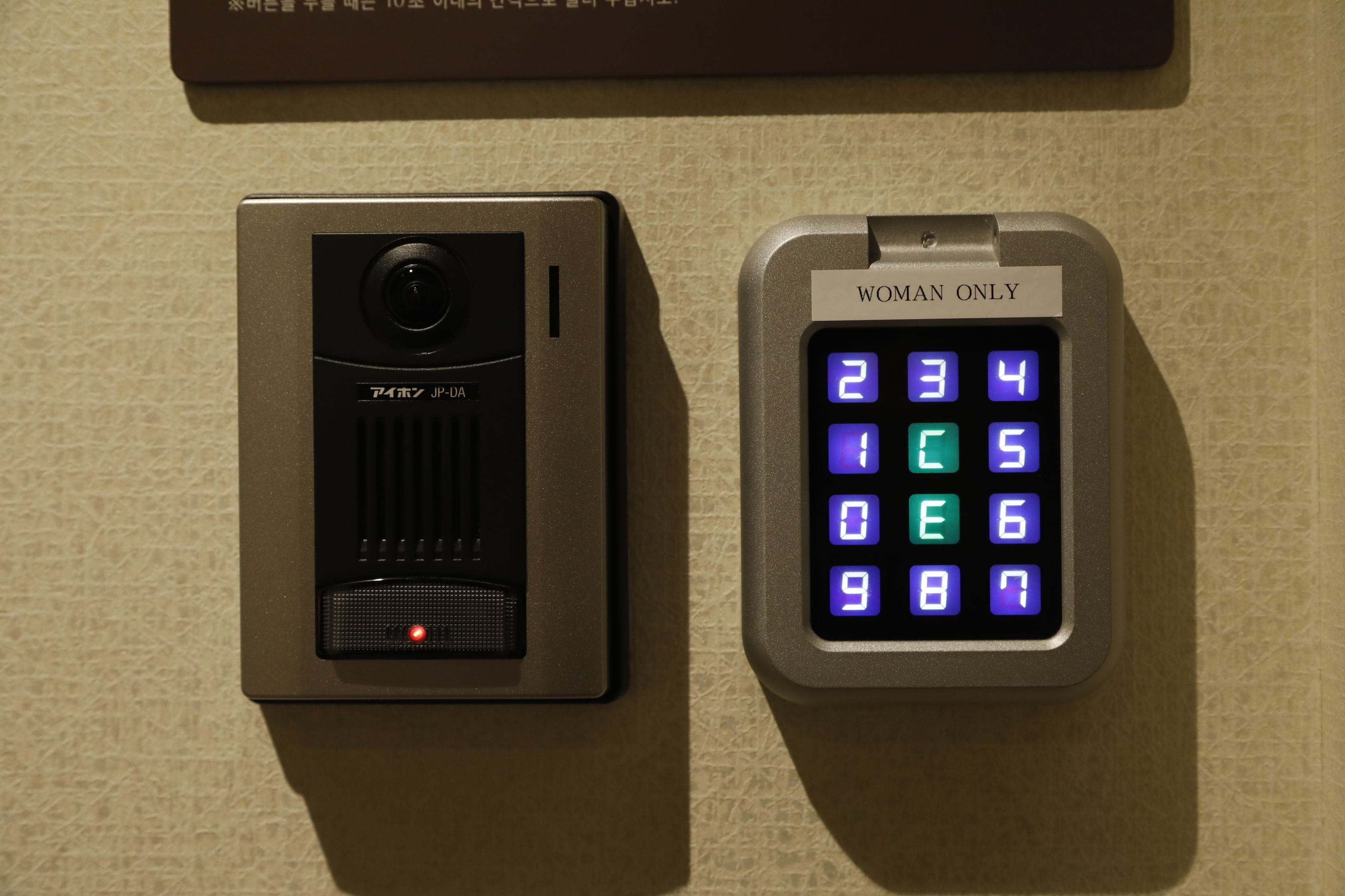 A keypad with a "WOMAN ONLY" sign and a security camera.