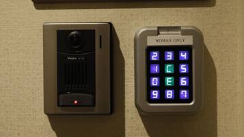 A keypad with a "WOMAN ONLY" sign and a security camera.