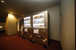 A row of vending machines in a hallway with a red carpet.
