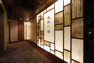 A hallway with a wooden floor and a wall with a decorative panel featuring Japanese characters.