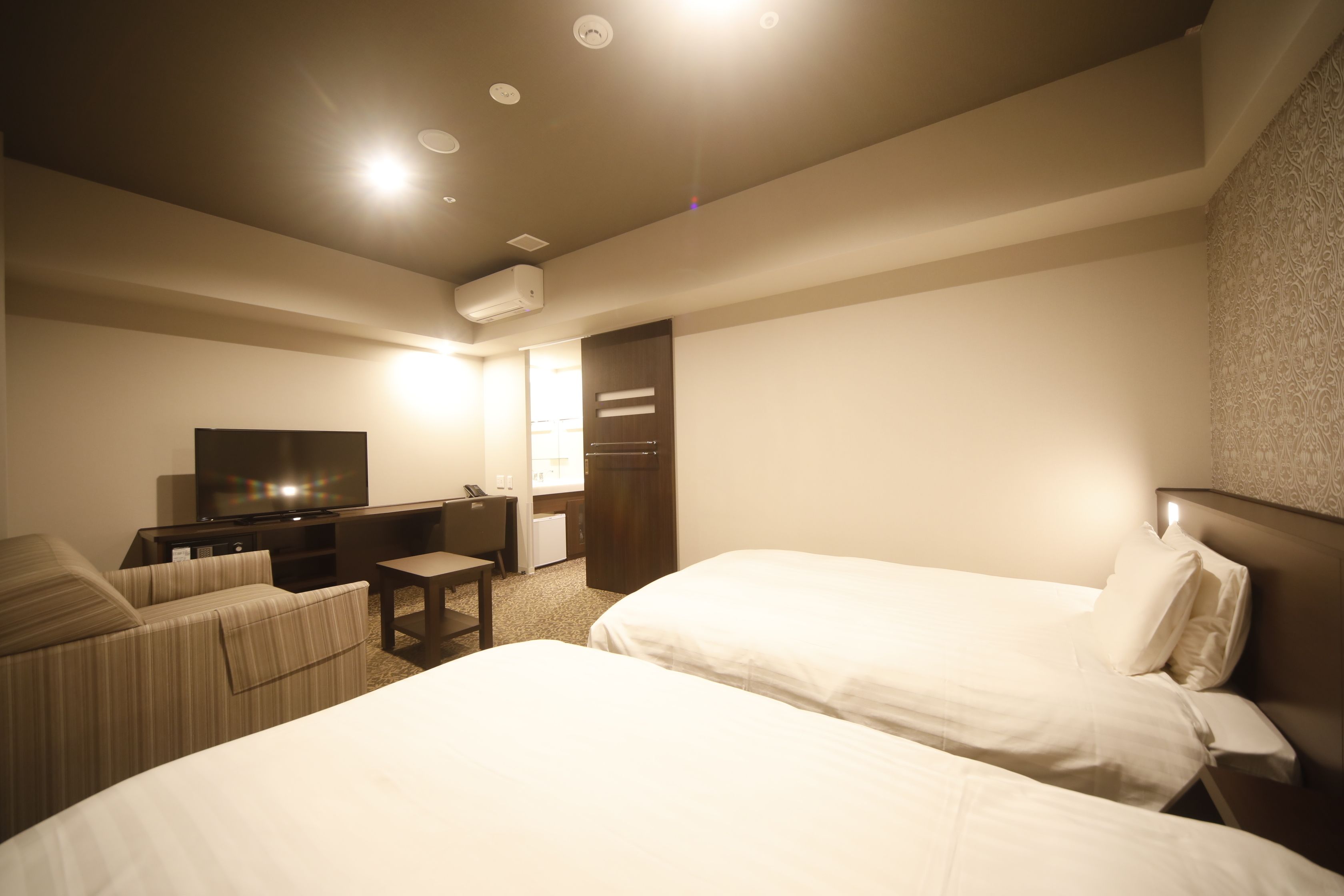 Une chambre d’hôtel avec deux lits, un bureau, une télévision et une armoire.