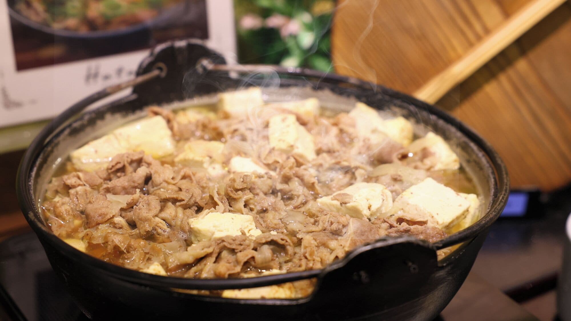 A hot pot with tofu and meat.