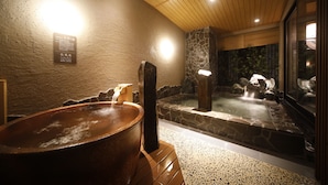 A hot spring bath area with a large stone basin, a wooden structure, and a stone wall with a bamboo backdrop. - Dormy Inn Premium Osaka Kitahama Hot Springs (Osaka)