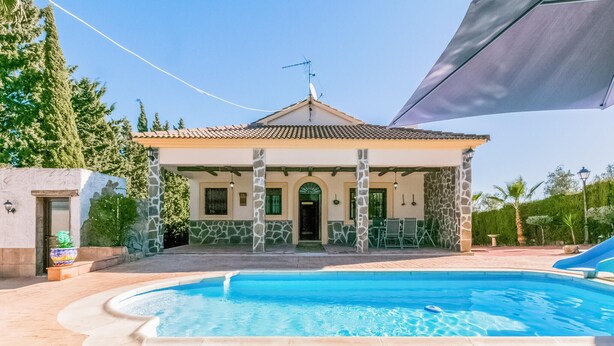 A two-story house with a swimming pool in front.