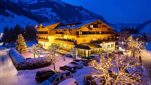 Un hotel de varios pisos con restaurante y cafetería, rodeado de árboles nevados y montañas.