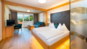Habitación de hotel con cama, televisión, sofá y vista a las montañas.