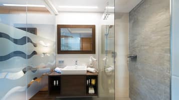 Un baño moderno con cabina de ducha de vidrio, tocador de madera y un espejo grande.
