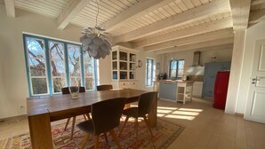 Una cocina amplia con una mesa y sillas de madera, un refrigerador rojo y vistas al exterior a través de ventanas grandes.