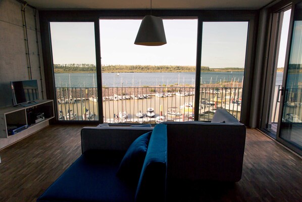 A modern living room with a large window overlooking a marina.