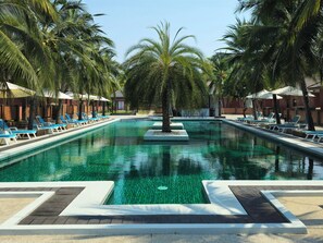 Une piscine avec des chaises longues et des palmiers.