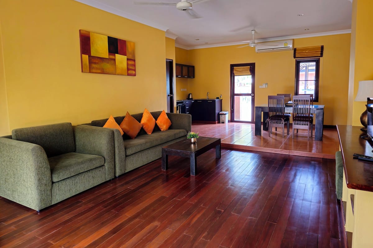 A living room with a sofa, coffee table, and a dining area with chairs and a table.