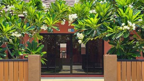 A pathway leading to a building with a red facade, surrounded by lush green plants and white flowers. - Baan Me Suk Spa & Resort Hua-Hin (Cha-am)