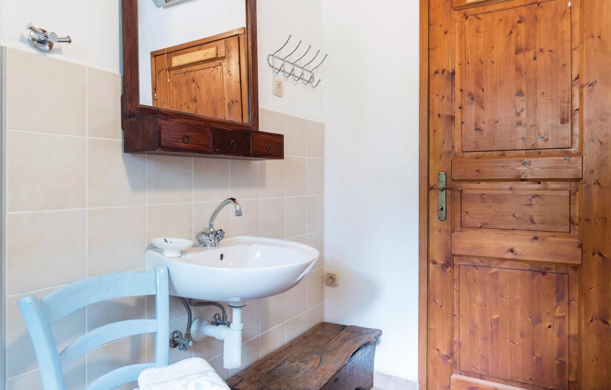 A bathroom with a wooden door, a white sink, a mirror, and a towel rack.