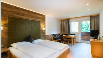 Un dormitorio con cama, escritorio, silla, televisor y ventana.