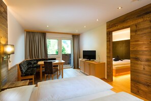 Quarto de hotel com cama, escrivaninha, cadeira, televisão e guarda-roupa.