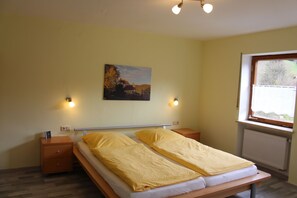 Ein Zimmer mit einem Bett, Nachttischen, einem Bild und einem Fenster.