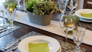 A dining table set with plates, glasses, and a potted plant.