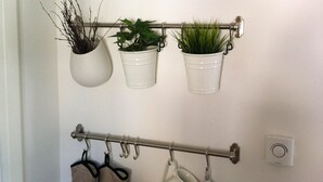 A wall-mounted rack with potted plants, a clock, and hanging kitchen items.