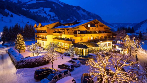 Ein mehrstöckiges Hotel mit Restaurant und Café, umgeben von schneebedeckten Bäumen und Bergen.