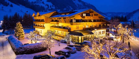 A multi-story hotel with a restaurant and cafe, surrounded by snow-covered trees and mountains.