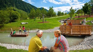 Eine Flusslandschaft mit einer Holzbrücke, Picknicktischen und einer natürlichen Umgebung.