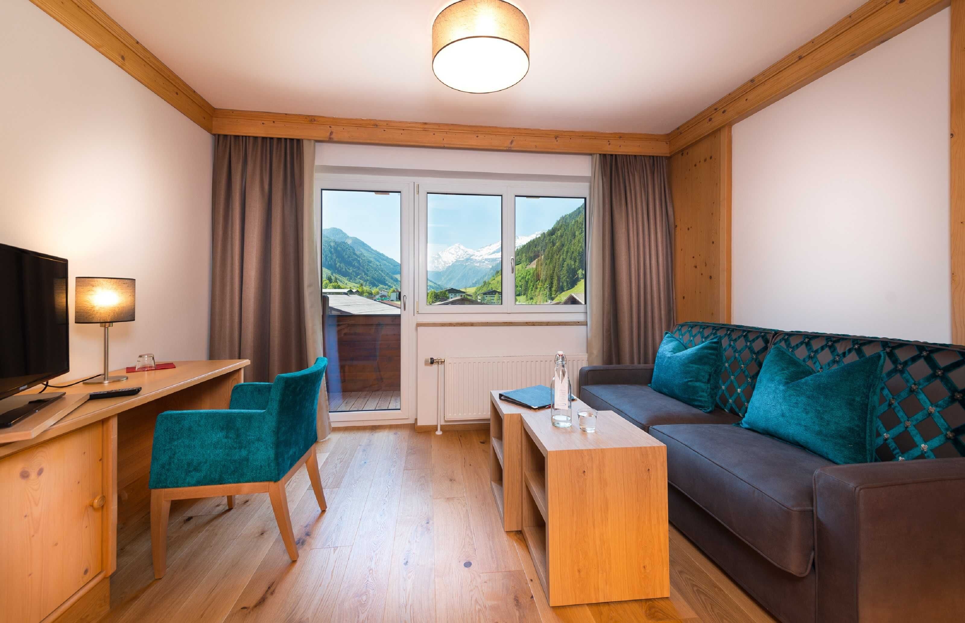 Una habitación con techo de madera, un sofá, un escritorio, una silla, un televisor y una ventana con vista a la montaña.