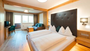 Ein Hotelzimmer mit einem großen Bett, einem Schreibtisch, einem Sessel und einem Fernseher.