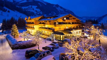 Un hotel de varios pisos con restaurante y cafetería, rodeado de árboles nevados y montañas.