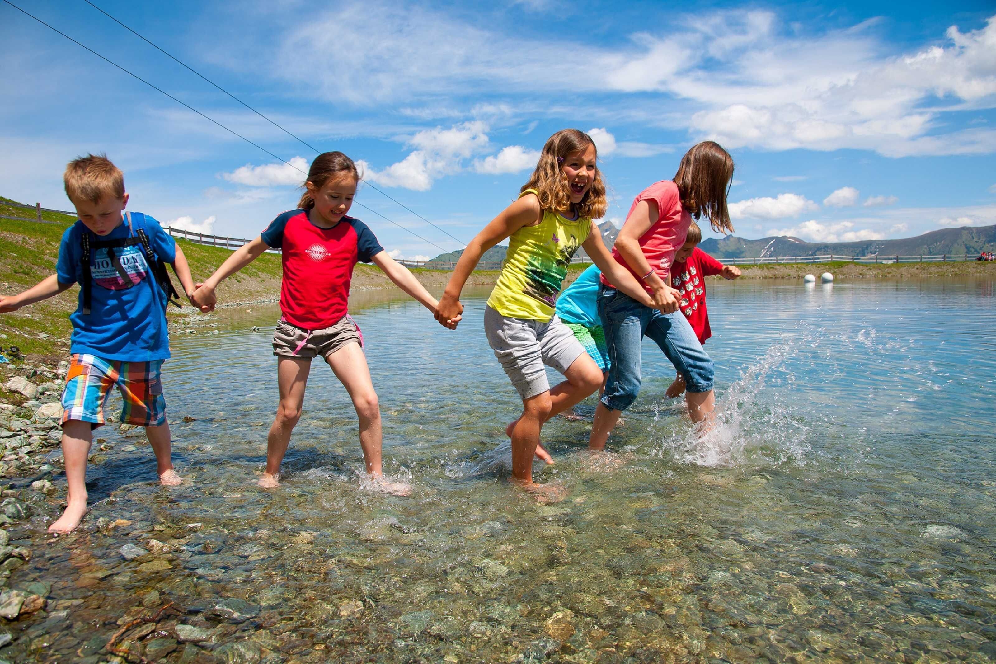 A group of people holding hands and walking through shallow water.