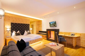 Een moderne hotelkamer met een bed, een bureau, een stoel, een open haard en een televisie.
