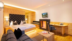 Een moderne hotelkamer met een bed, een bureau, een stoel, een open haard en een televisie.