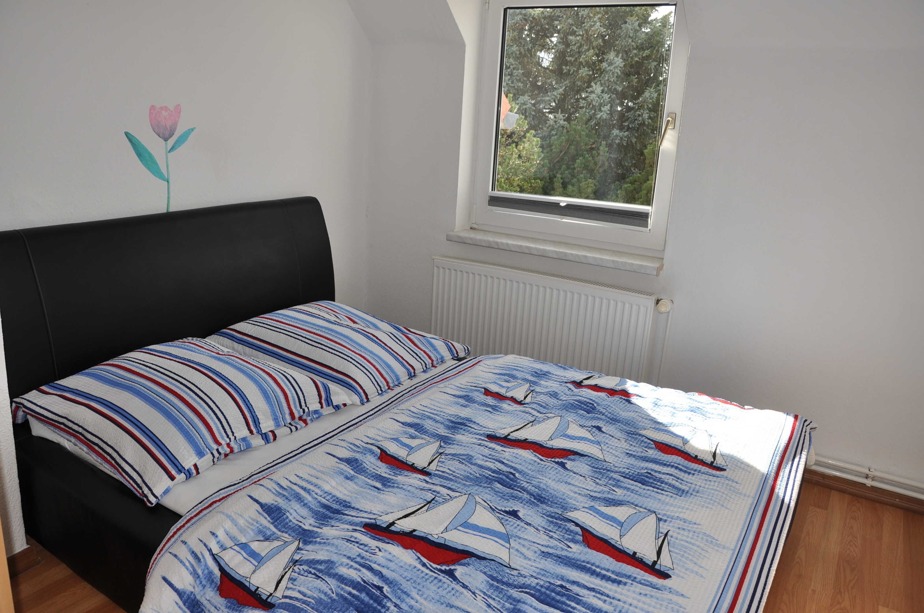 A bedroom with a bed, a window, and a radiator.