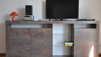A modern entertainment unit with a flat-screen TV, a sound system, and a lamp.
