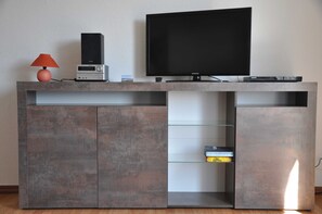 Un mueble moderno de entretenimiento con un televisor de pantalla plana, un sistema de sonido y una lámpara.