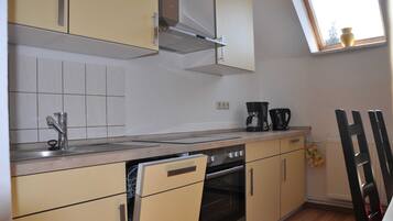 A kitchen with a dishwasher, oven, and a coffee maker on the counter.